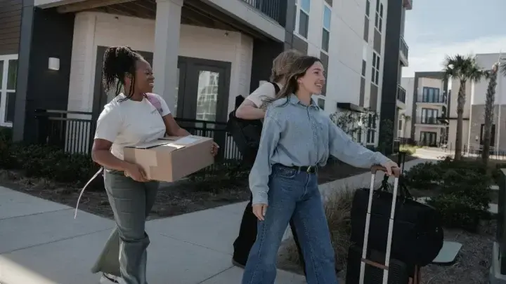 People carrying boxes and luggage outside an apartment building, illustrating temporary housing after an insured home loss
