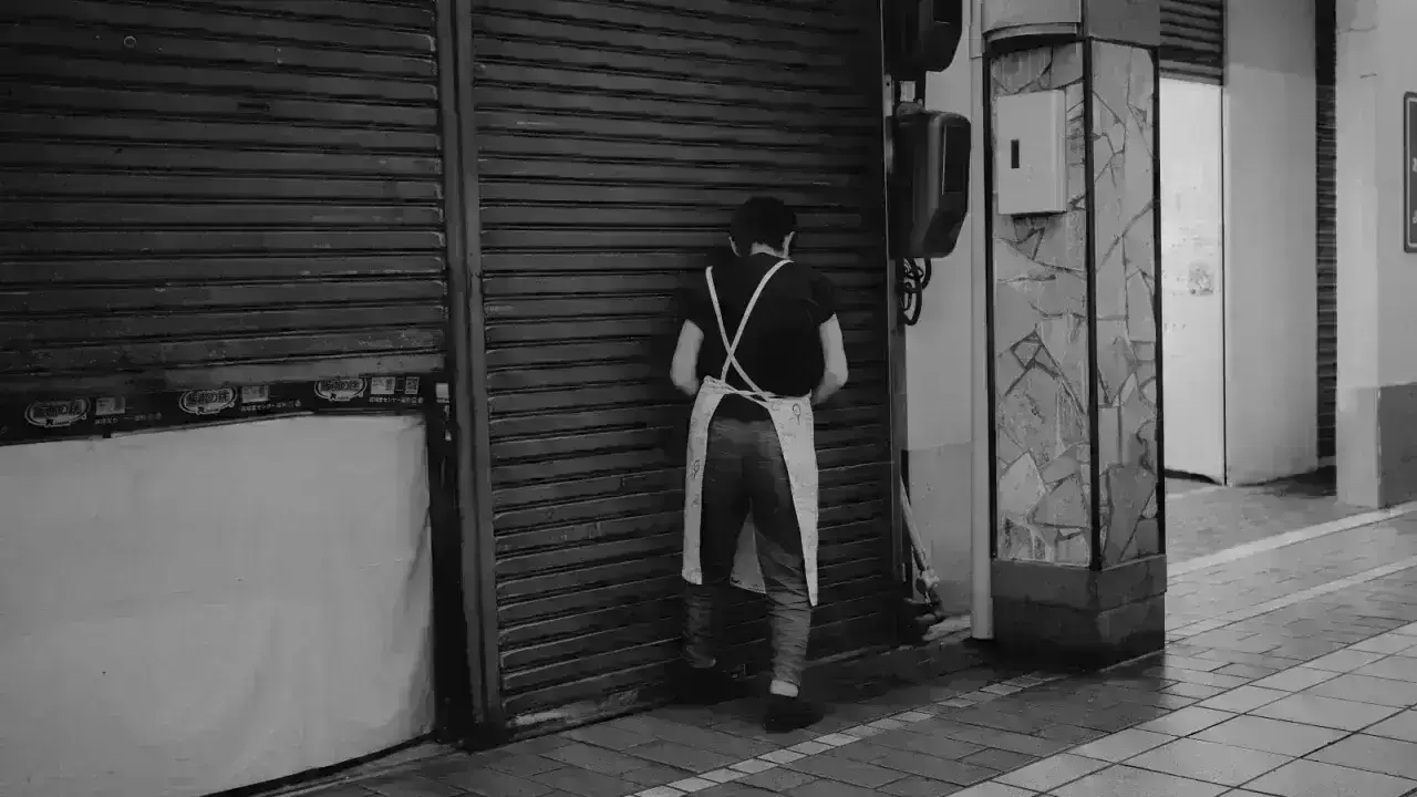 Worker closing a storefront, illustrating business interruption and lost-income risk