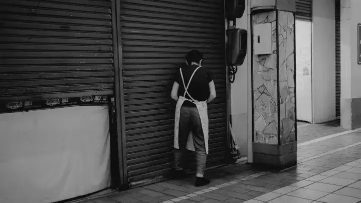 Worker closing a storefront, illustrating business interruption and lost-income risk
