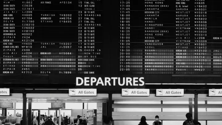 Travelers walking past an airport departure board, illustrating trip cancellation decisions