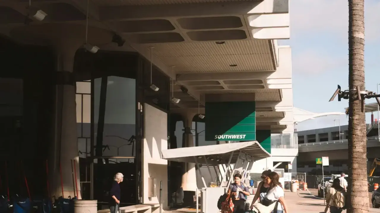 Travelers carrying luggage outside an airport terminal, illustrating European travel insurance