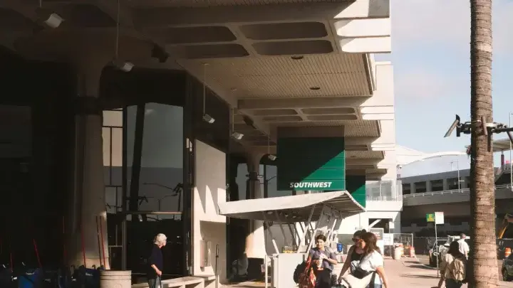 Travelers carrying luggage outside an airport terminal, illustrating European travel insurance