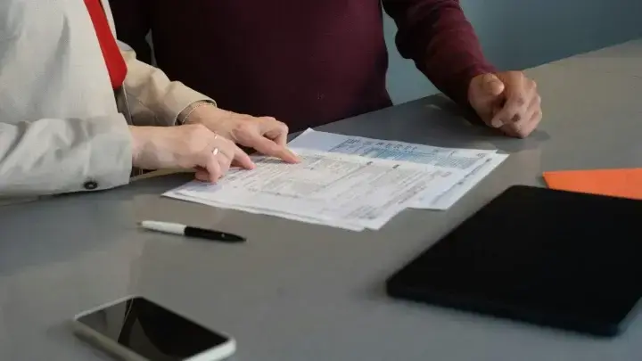 Two people reviewing financial documents, illustrating life insurance beneficiary planning