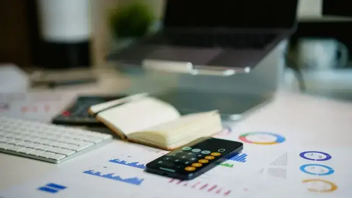 Financial charts and calculator on an office desk, illustrating excess-of-loss reinsurance structure and loss aggregation