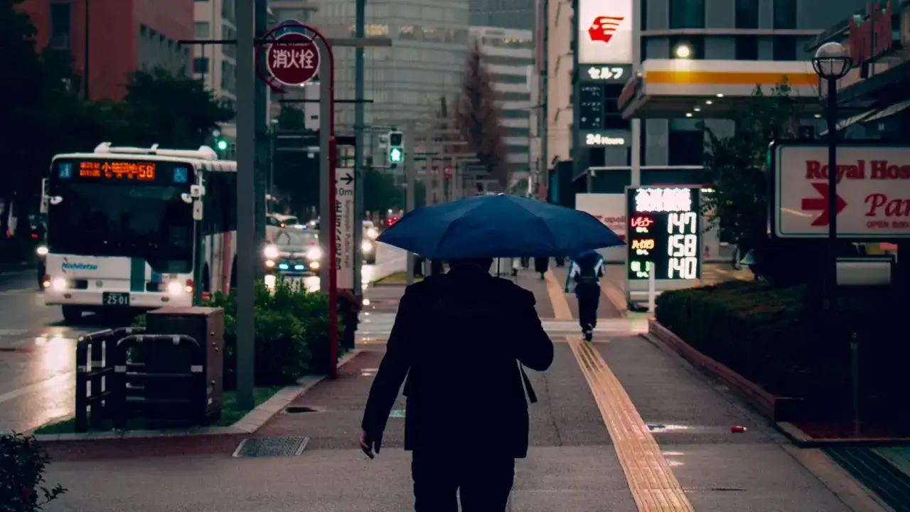 Person walking under an umbrella in a city, illustrating umbrella liability insurance