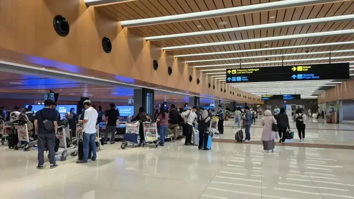 Travelers moving through an airport terminal with luggage, illustrating travel insurance