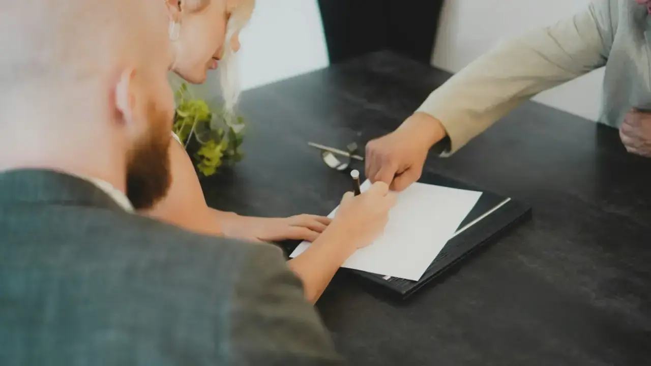 Couple signing financial documents at a desk for a life and AD&D insurance comparison