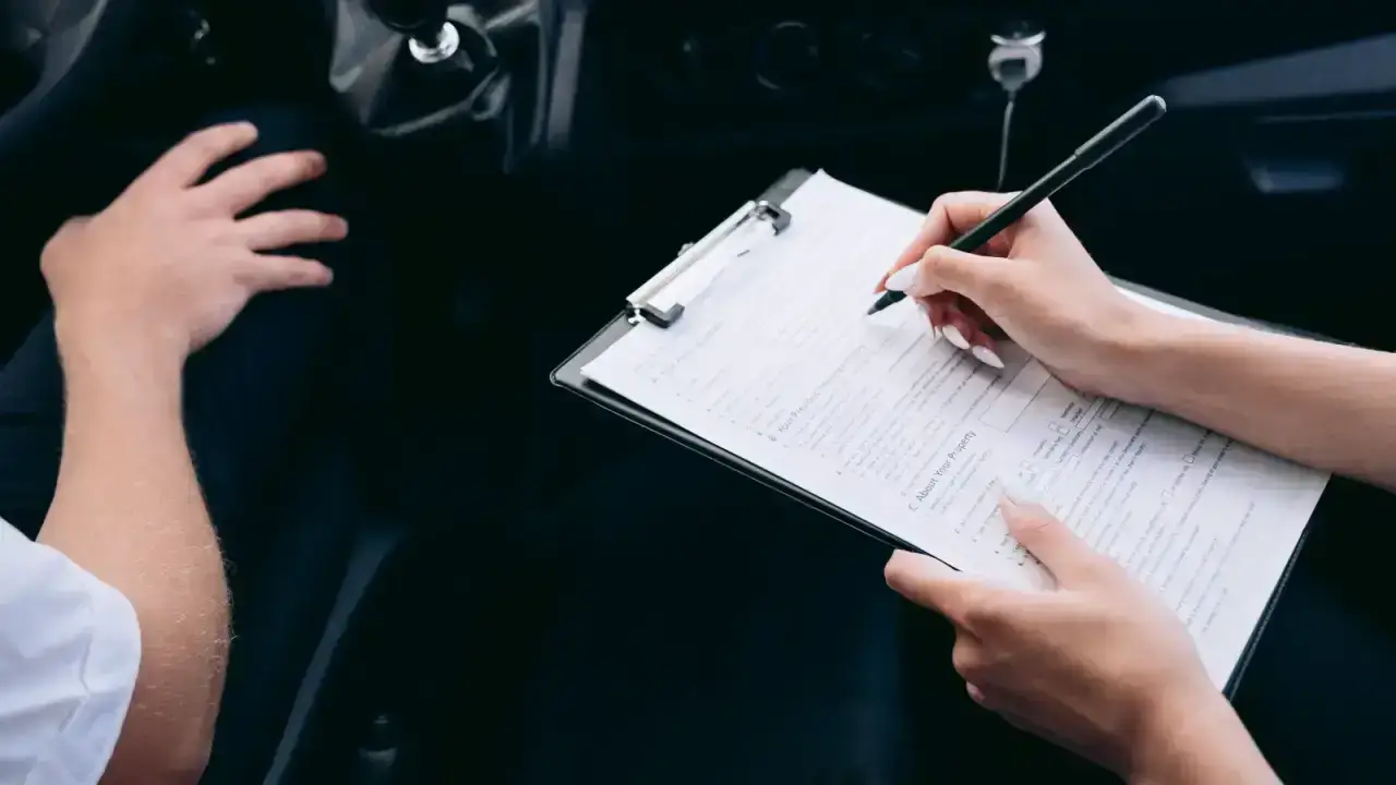 Driver reviewing insurance paperwork on a clipboard inside a car before restoring auto coverage