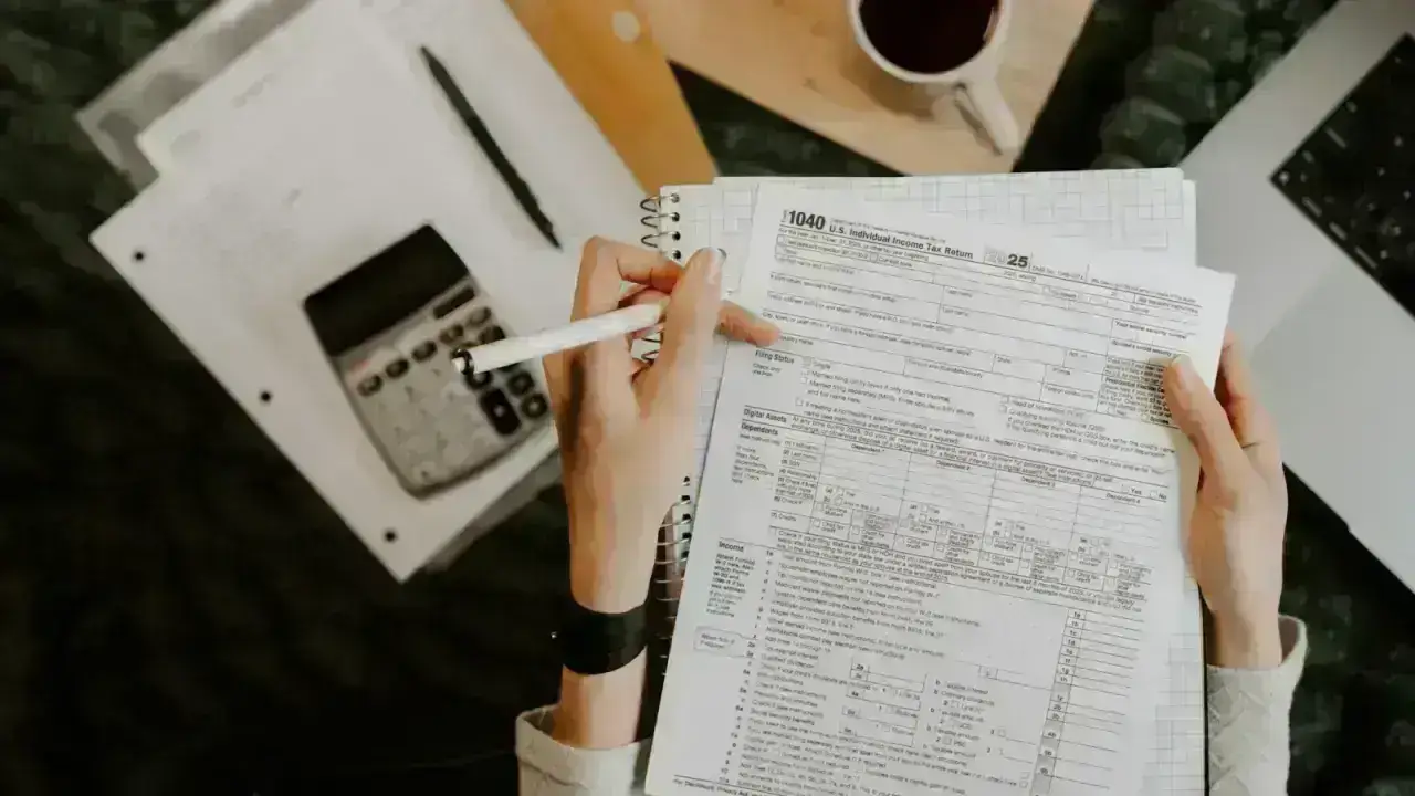 Person reviewing financial documents with a calculator and laptop illustrating credit-based insurance scoring