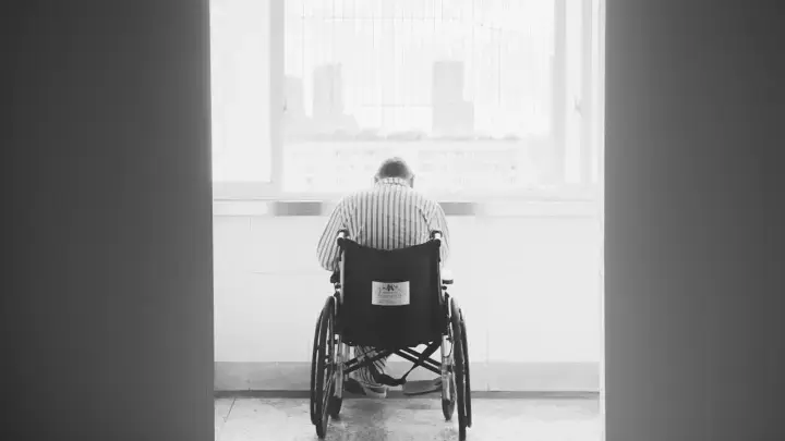 Patient using a wheelchair in a healthcare setting, illustrating the financial impact that critical illness insurance is designed to supplement