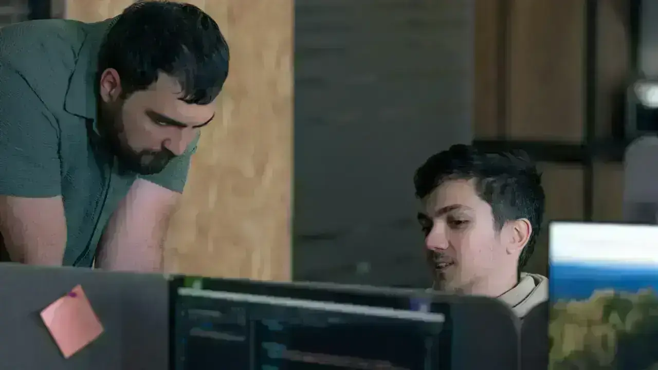 Two technology professionals examining computer screens in an office, illustrating coordinated cyber incident and insurance claim response