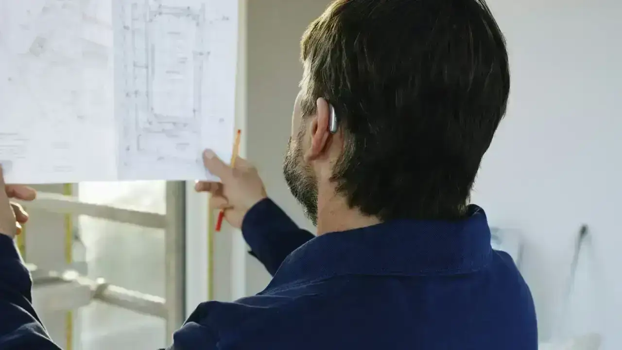 Construction professional reviewing building plans, illustrating homeowners insurance rebuilding cost and replacement coverage