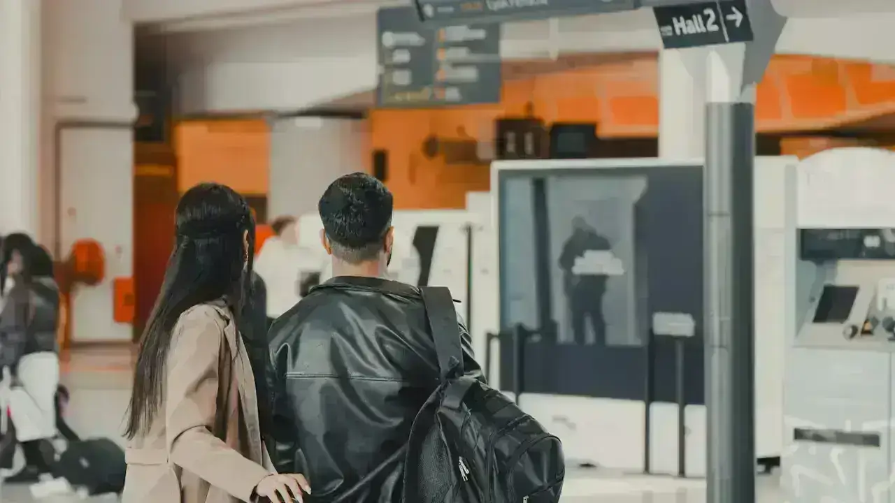 Travelers checking a terminal departure board illustrating canceled and delayed flight refund and travel insurance questions