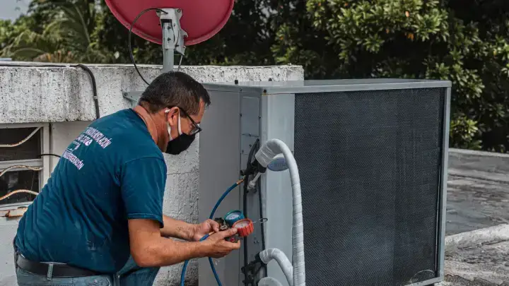 Technician inspecting a residential air conditioning unit for an equipment breakdown coverage guide