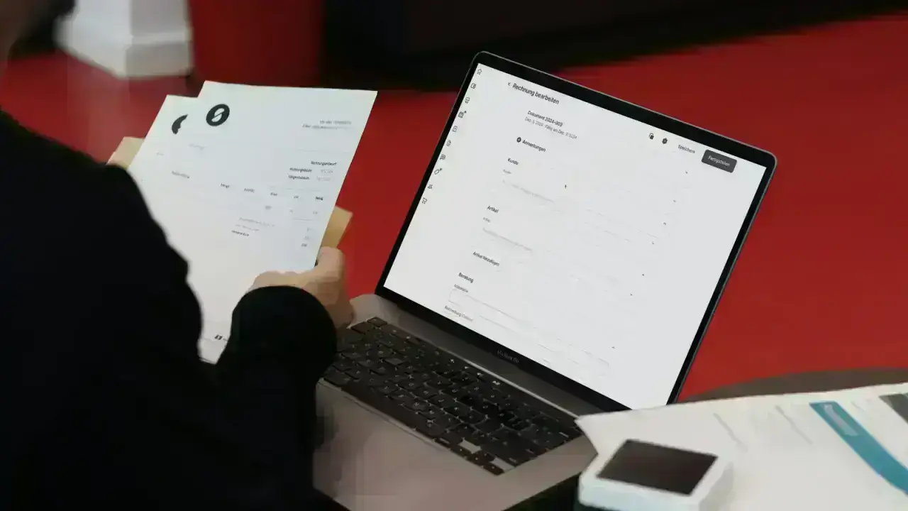 Professional working with a laptop and paperwork at a desk, illustrating insurance producer licensing applications and compliance