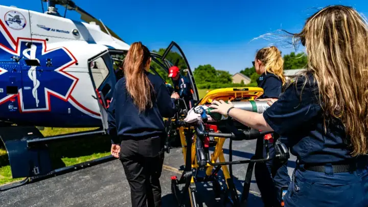 Medical personnel loading a patient into an air ambulance helicopter, illustrating emergency medical evacuation insurance for travelers