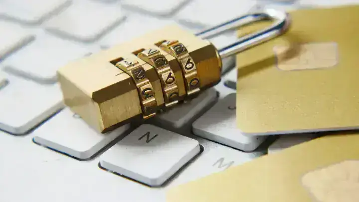 Combination lock beside digital payment cards and a keyboard, illustrating cyber security and data privacy liability