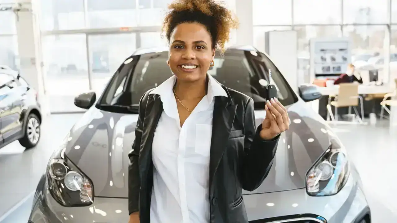 Driver holding new car keys at a dealership illustrating newly acquired vehicle insurance coverage