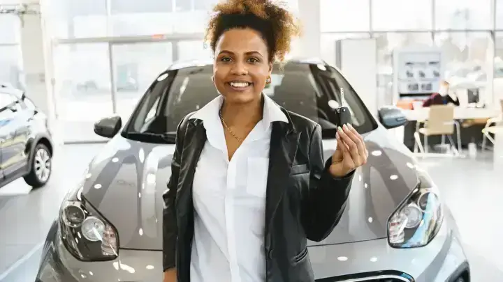 Driver holding new car keys at a dealership illustrating newly acquired vehicle insurance coverage