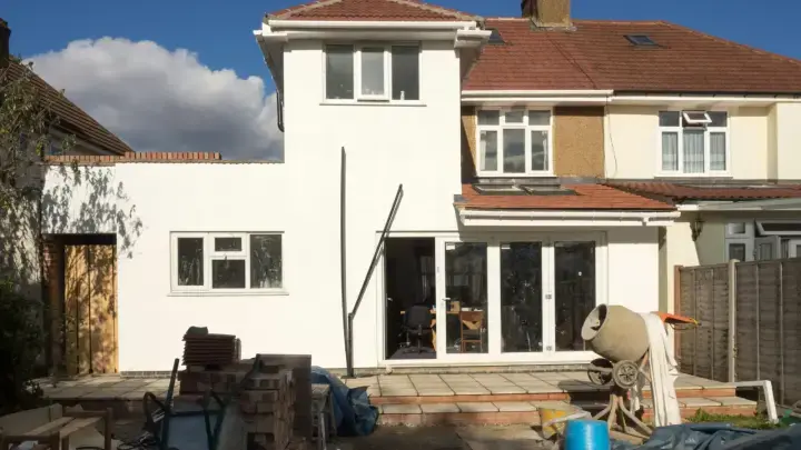 House undergoing renovation with exposed construction, illustrating building code upgrade costs after an insured loss