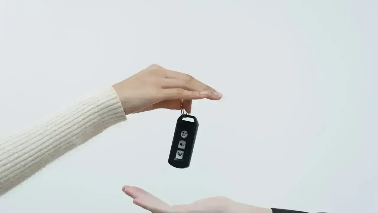 Hands exchanging car keys, illustrating permissive use when another driver borrows an insured vehicle