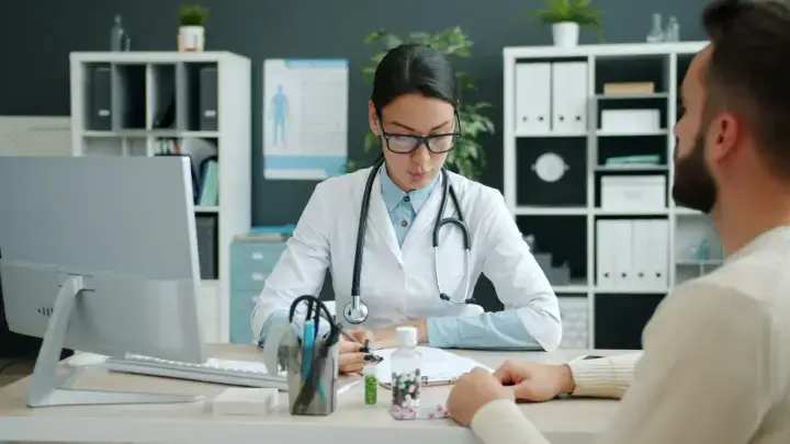 Doctor consulting with a patient over medical paperwork, illustrating coordination between primary and secondary health insurance