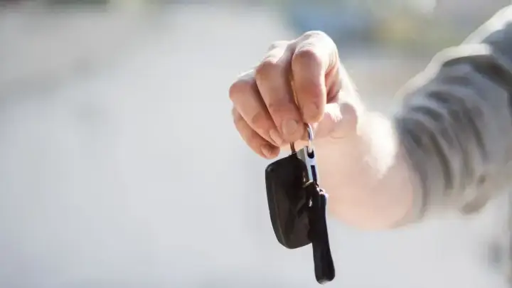 Handing over car keys illustrating rental car damage coverage and travel insurance choices