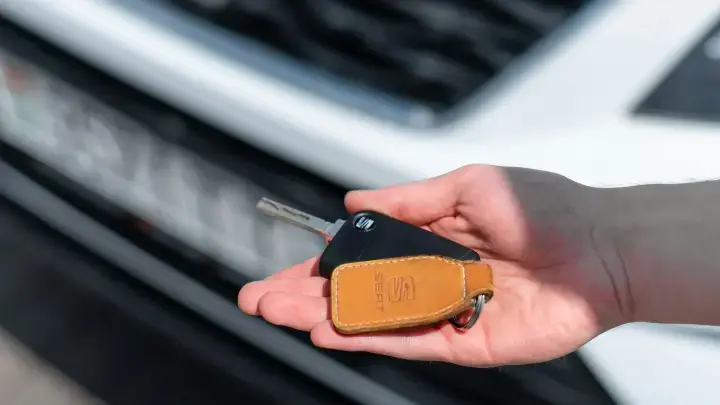 Person holding a car key inside a vehicle, illustrating rental car insurance choices