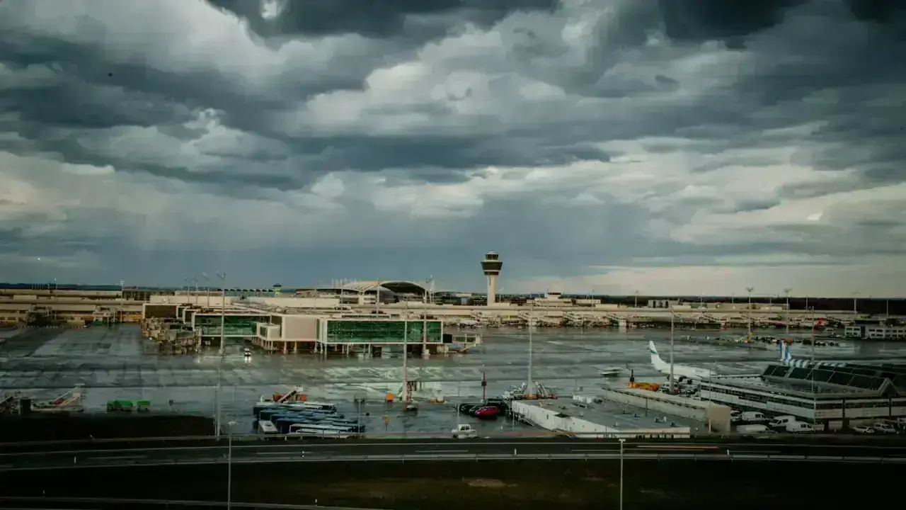 Airport terminal beneath dramatic storm clouds, illustrating hurricane and severe-weather travel insurance disruptions