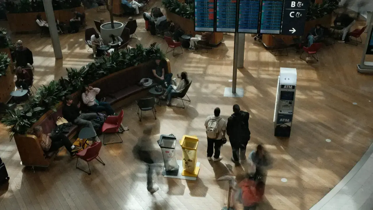 Travelers waiting beneath an airport departure board, illustrating trip delay and trip interruption insurance benefits