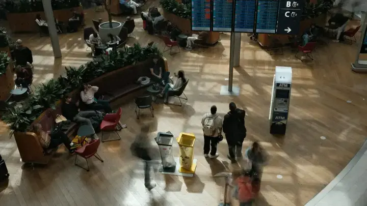 Travelers waiting beneath an airport departure board, illustrating trip delay and trip interruption insurance benefits